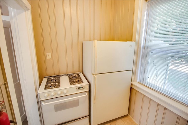 kitchen featuring a healthy amount of sunlight, white appliances, and wood walls