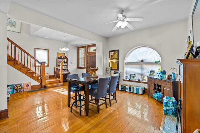 dining area featuring ceiling fan with notable chandelier, light hardwood / wood-style flooring, and a healthy amount of sunlight