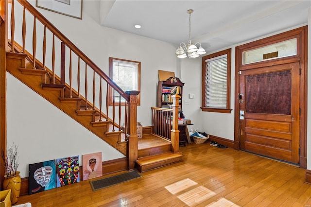 foyer featuring hardwood / wood-style flooring, a healthy amount of sunlight, and a notable chandelier