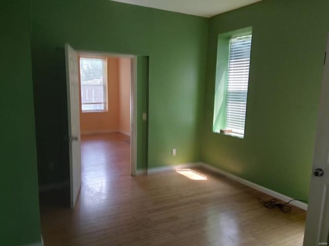 empty room featuring a wealth of natural light, baseboards, and wood finished floors