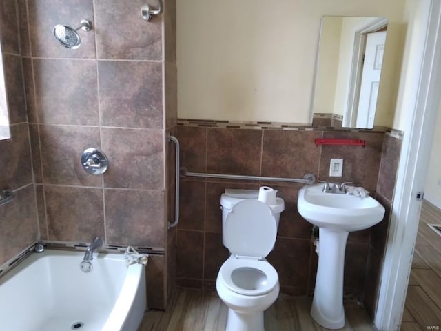 bathroom featuring a sink, tile walls, toilet, shower / bath combination, and wood finished floors