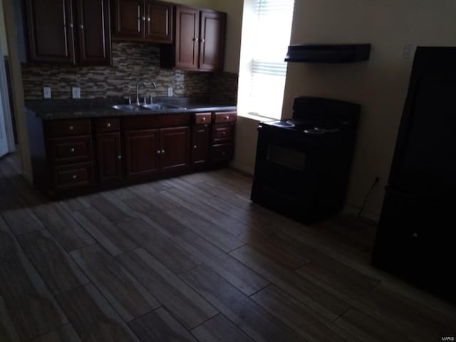 kitchen featuring tasteful backsplash, exhaust hood, a sink, dark wood finished floors, and electric range