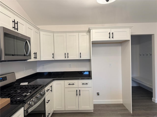 kitchen featuring dark hardwood / wood-style flooring, white cabinets, stainless steel appliances, and lofted ceiling