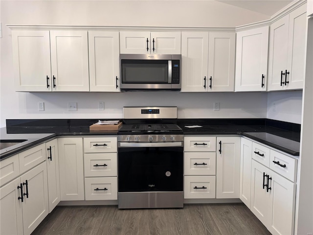 kitchen featuring vaulted ceiling, white cabinetry, stainless steel appliances, and dark wood-type flooring