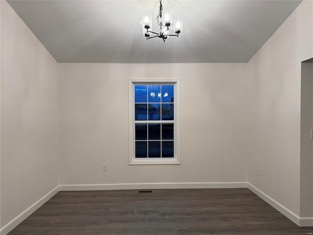 empty room with dark hardwood / wood-style floors and an inviting chandelier