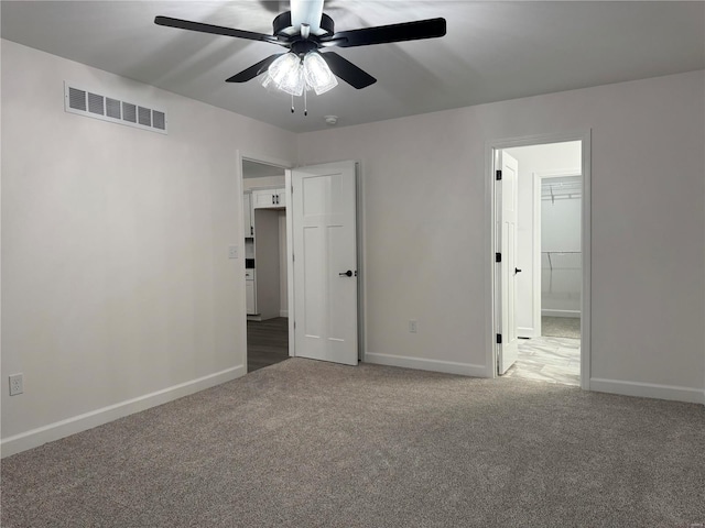 unfurnished bedroom featuring carpet flooring, a closet, a spacious closet, and ceiling fan