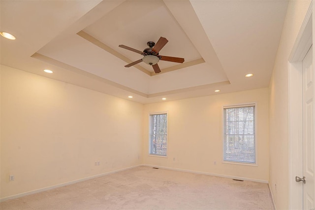 carpeted empty room with a tray ceiling and ceiling fan