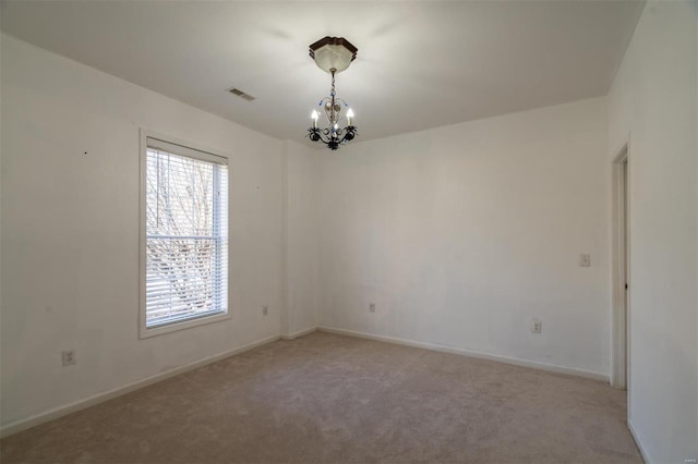 carpeted spare room featuring an inviting chandelier and a wealth of natural light