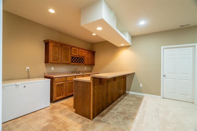 kitchen featuring kitchen peninsula, refrigerator, sink, and light tile patterned floors