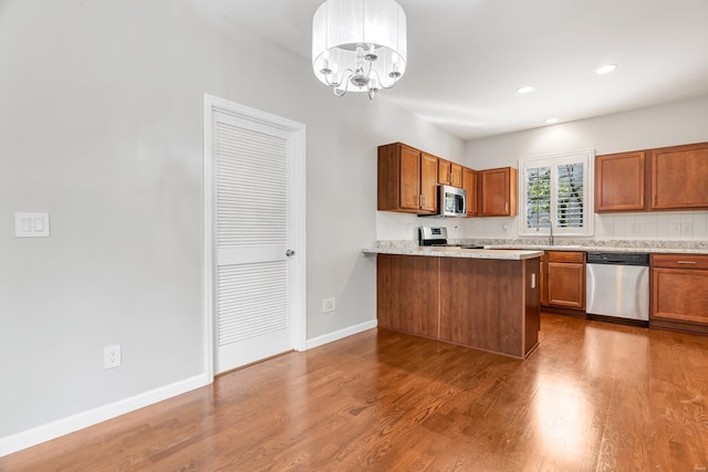 kitchen with an inviting chandelier, appliances with stainless steel finishes, hanging light fixtures, and dark wood-type flooring