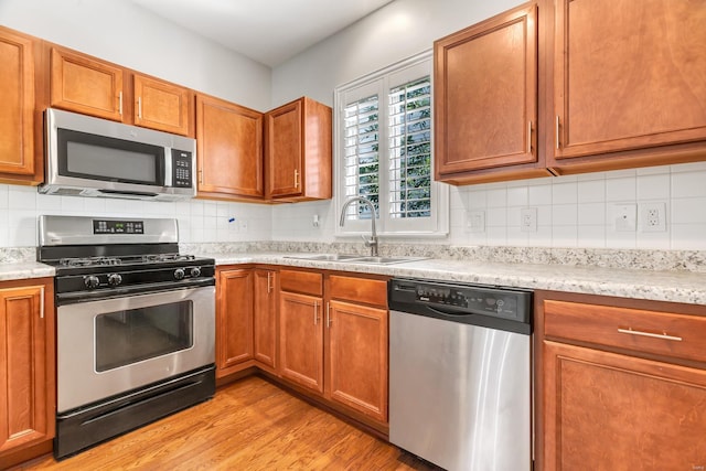 kitchen featuring backsplash, sink, light hardwood / wood-style flooring, and stainless steel appliances