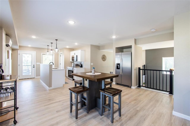 dining room featuring a wall unit AC, light hardwood / wood-style flooring, and sink