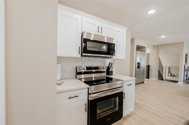 kitchen featuring light hardwood / wood-style floors, decorative backsplash, white cabinetry, and stainless steel appliances