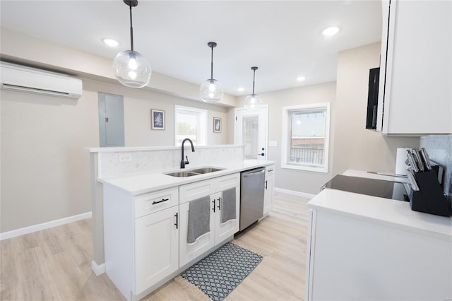 kitchen with a wall unit AC, hanging light fixtures, sink, stainless steel dishwasher, and white cabinetry