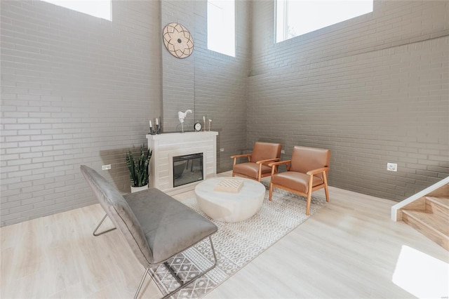 living room with a towering ceiling, light hardwood / wood-style flooring, and brick wall