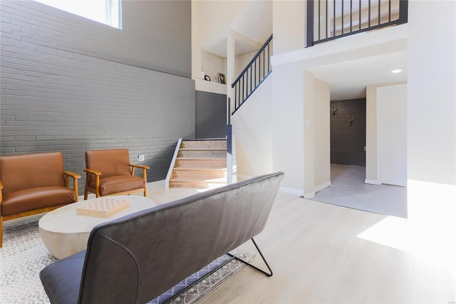 stairs with brick wall, a high ceiling, and wood-type flooring