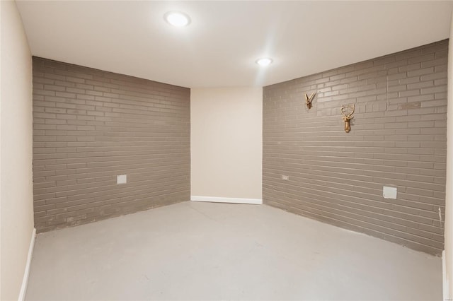 empty room featuring brick wall and concrete flooring