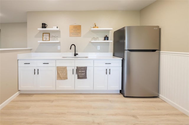 kitchen featuring white cabinetry, light hardwood / wood-style flooring, sink, and stainless steel fridge