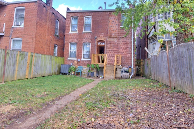 rear view of property featuring cooling unit and a yard