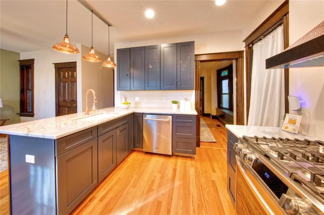 kitchen with hanging light fixtures, sink, light stone countertops, light wood-type flooring, and appliances with stainless steel finishes