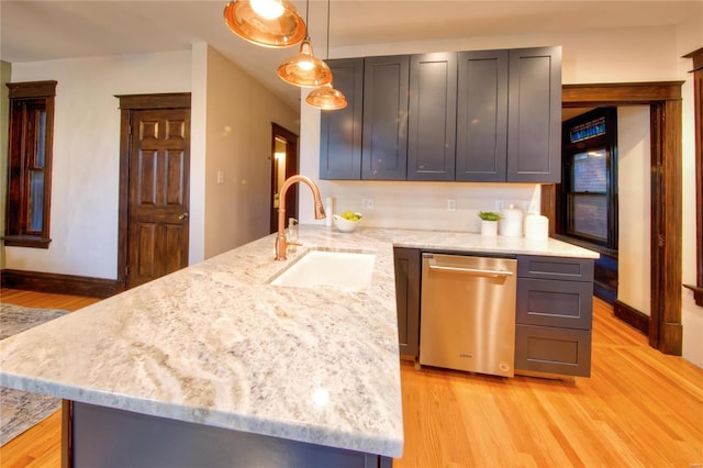 kitchen featuring light stone countertops, sink, hanging light fixtures, stainless steel dishwasher, and light hardwood / wood-style flooring