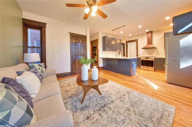 living room featuring sink, light hardwood / wood-style floors, and ceiling fan