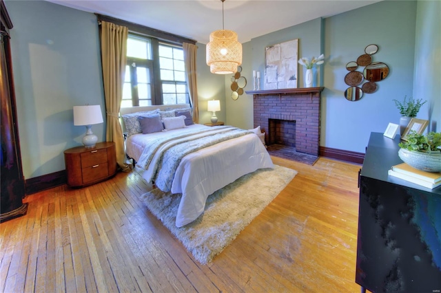 bedroom featuring light wood-type flooring and a fireplace