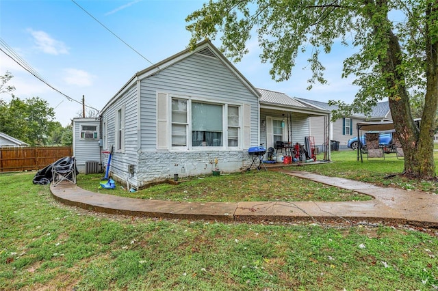 bungalow-style home featuring cooling unit, a front lawn, and a patio area