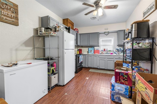 kitchen with gray cabinets, dark hardwood / wood-style floors, fridge, ceiling fan, and black / electric stove