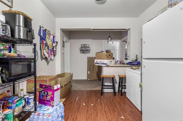 interior space with washer / dryer, white refrigerator, hanging light fixtures, and hardwood / wood-style floors