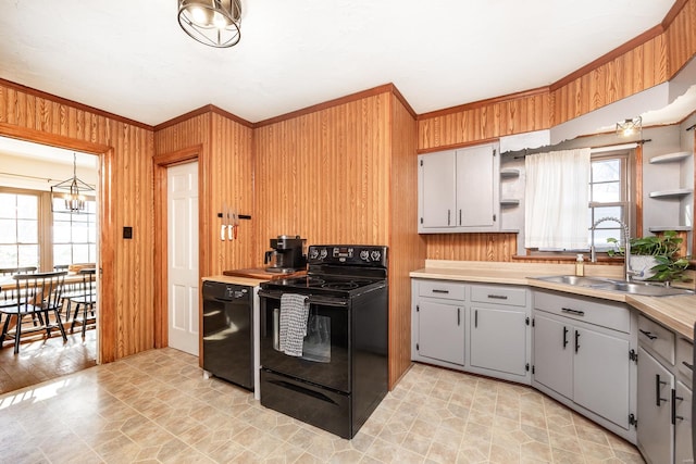 kitchen featuring black appliances, sink, wood walls, a chandelier, and gray cabinetry