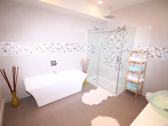 bathroom with tile walls, independent shower and bath, and tile patterned floors