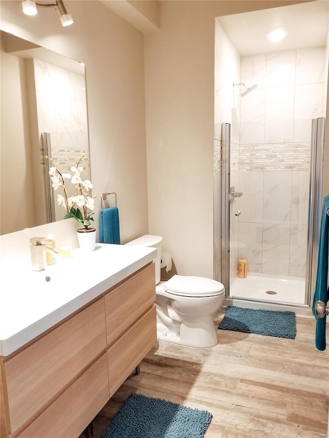 bathroom featuring an enclosed shower, hardwood / wood-style flooring, vanity, and toilet