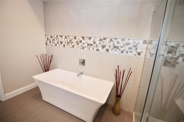 bathroom with tile walls and shower with separate bathtub