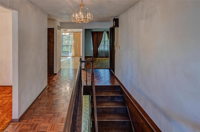 stairway with parquet flooring and ceiling fan with notable chandelier