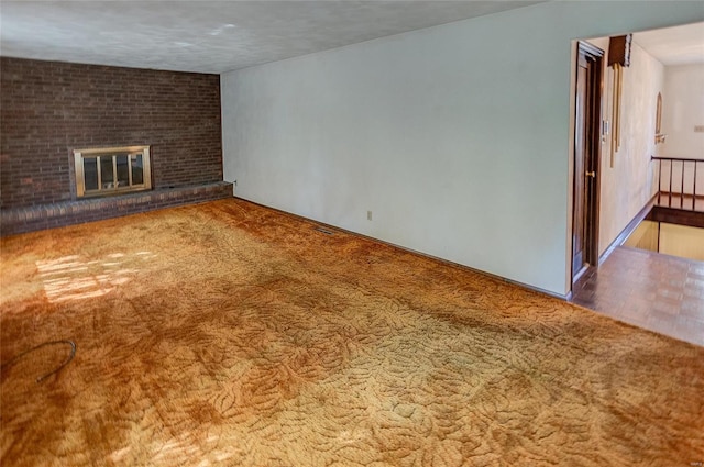 unfurnished living room with carpet, a brick fireplace, and a textured ceiling