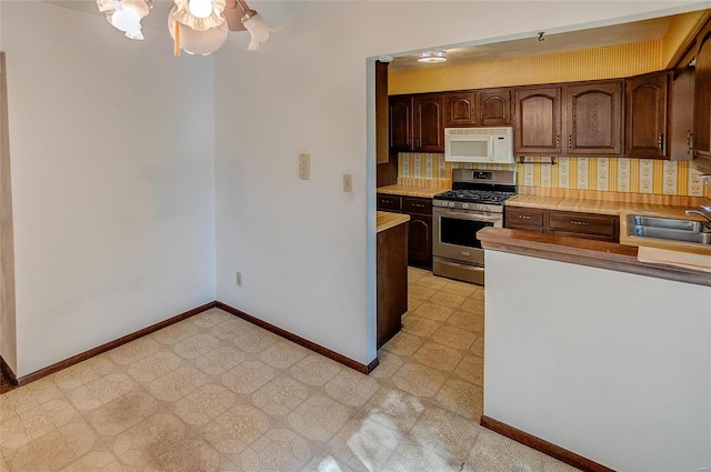 kitchen with dark brown cabinets, stainless steel range with gas cooktop, sink, and tasteful backsplash