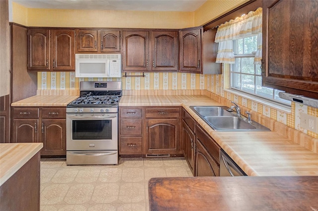 kitchen with tasteful backsplash, dark brown cabinets, appliances with stainless steel finishes, butcher block counters, and sink