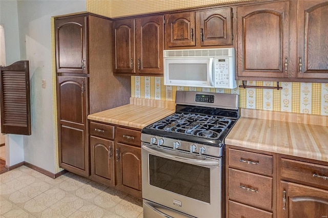 kitchen featuring stainless steel range with gas cooktop, butcher block counters, backsplash, and light tile patterned floors