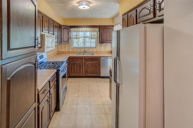 kitchen featuring dark brown cabinetry, sink, appliances with stainless steel finishes, and decorative backsplash