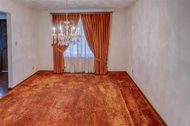 carpeted empty room featuring a notable chandelier