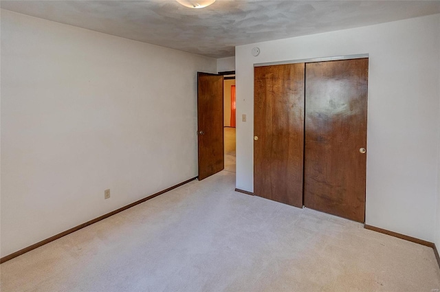 unfurnished bedroom featuring a textured ceiling, light colored carpet, and a closet