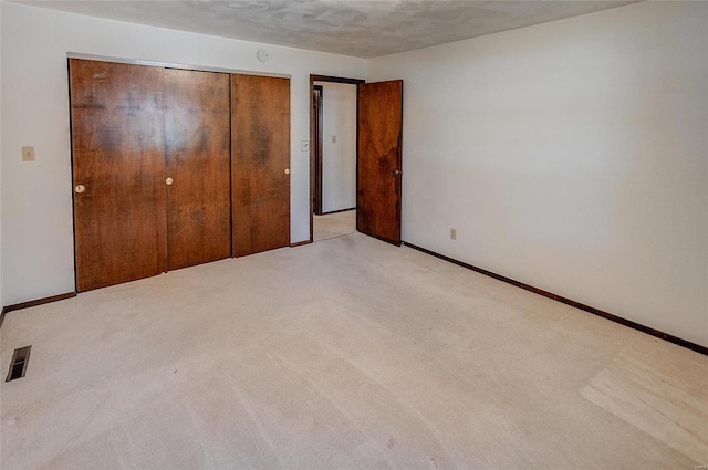 unfurnished bedroom with a closet, a textured ceiling, and light colored carpet