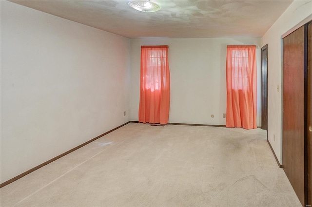 spare room featuring a textured ceiling and light colored carpet