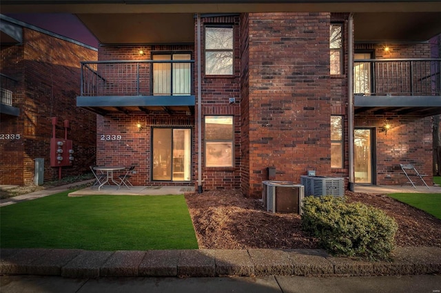 rear view of property with a balcony, a yard, and a patio