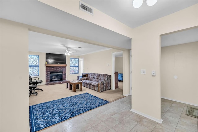 carpeted living room with ceiling fan, ornamental molding, and a brick fireplace