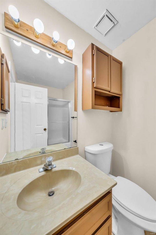 bathroom with vanity, toilet, and a shower with door