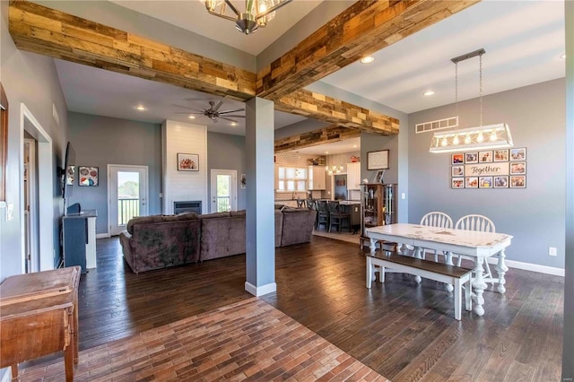 dining space featuring beamed ceiling, dark hardwood / wood-style floors, and a large fireplace