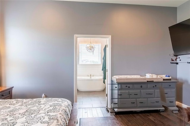 bedroom featuring ensuite bath and dark wood-type flooring