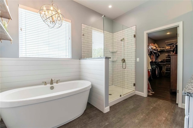 bathroom featuring independent shower and bath, hardwood / wood-style flooring, wooden walls, and a chandelier